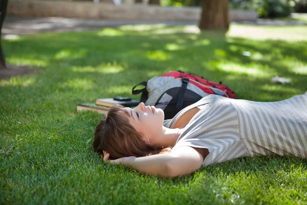 Девушка лежит на траве на лужайке кампуса — стоковое фото