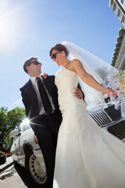 Verheugd huwelijksfeest paar met limo — Stockfoto