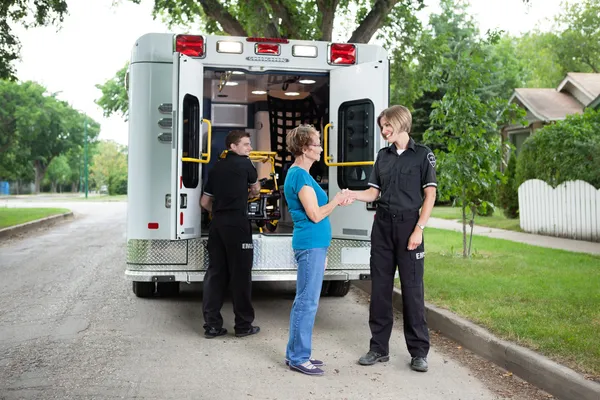 Oudere vrouw met ambulance personeel — Stockfoto