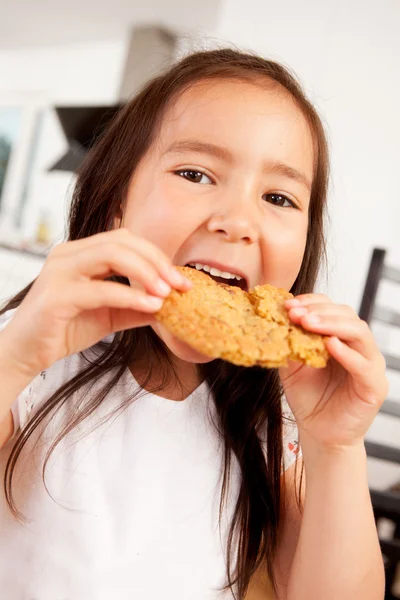 Menina nova comer biscoito — Fotografia de Stock
