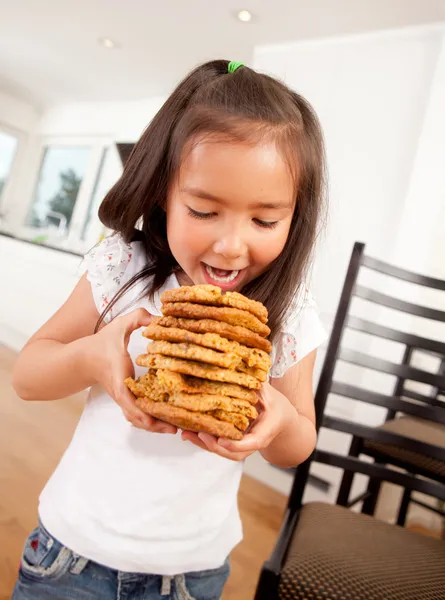 Jong meisje eten stapel van cookies — Stockfoto