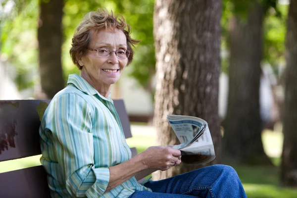 Vrouw lezing krant in park — Stockfoto