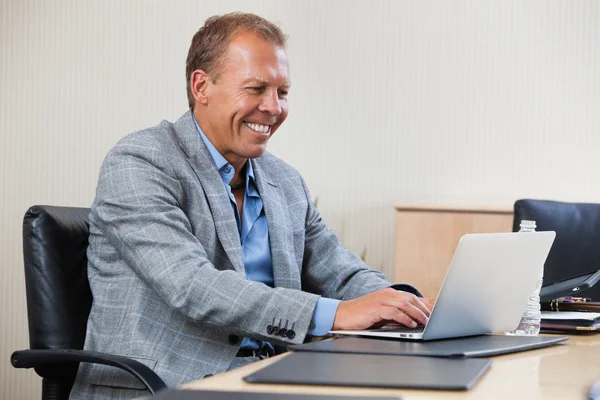 Веселый бизнесмен работает на ноутбуке — стоковое фото