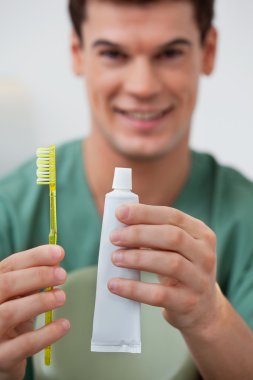 Dentist holding toothpaste and toothbrush clipart