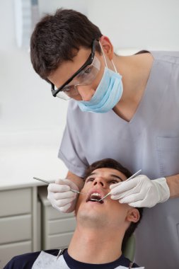 Dentist examining patient's teeth clipart