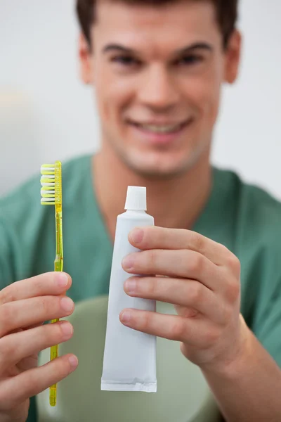 Dentista segurando pasta de dentes e escova de dentes — Fotografia de Stock
