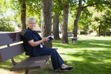 Woman reading book in a park clipart