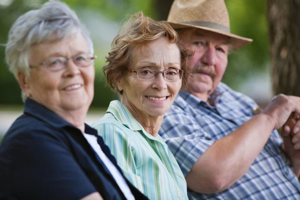 Senior friends sitting together in park — Stock Photo, Image
