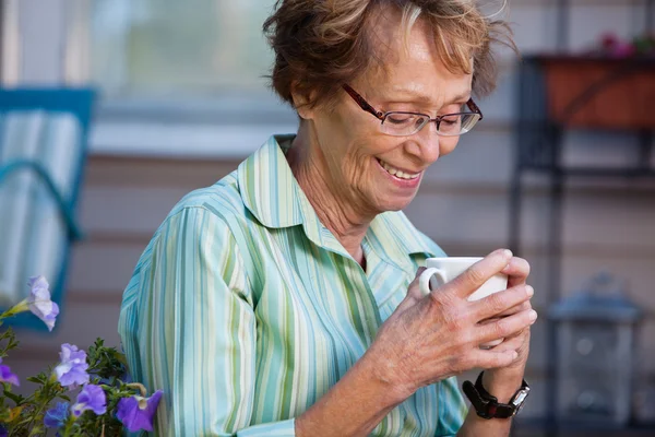 Старшая женщина с горячим напитком на открытом воздухе — стоковое фото