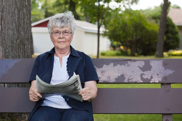 Seniorin liest Zeitung im Park — Stockfoto