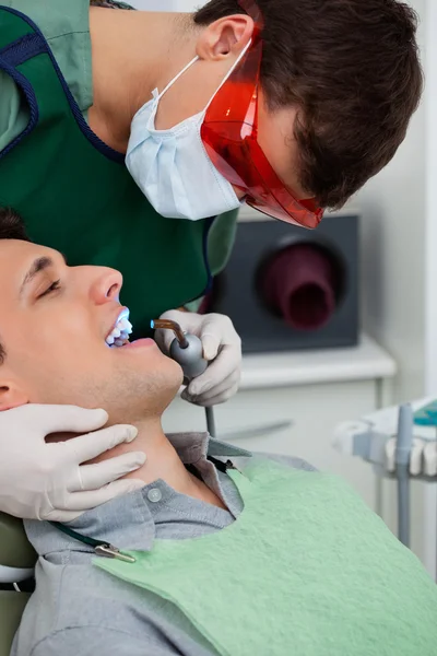 Dentista trabalhando em dente na clínica odontológica — Fotografia de Stock