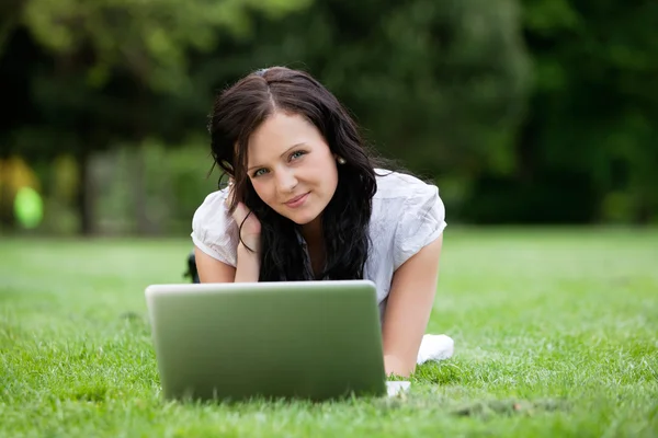 Hübsches Weibchen liegt mit Laptop im Gras — Stockfoto