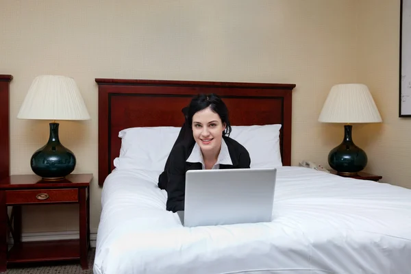 Podnikatelka, ležící na posteli s notebookem — Stock fotografie