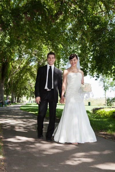Casal jovem recém-casado segurando as mãos — Fotografia de Stock