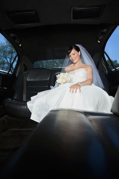 Невеста с цветочным букетом в лимузине — стоковое фото