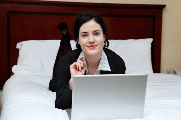 Usměvavá moderátorka leží na posteli s notebookem — Stock fotografie