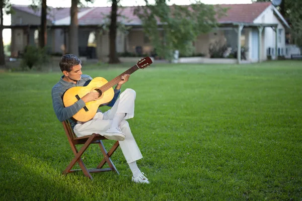 Man Playing Guitar in Lawn Stock Photo
