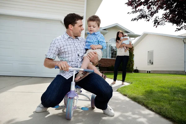 Pai brincalhão sentado no triciclo com o filho — Fotografia de Stock