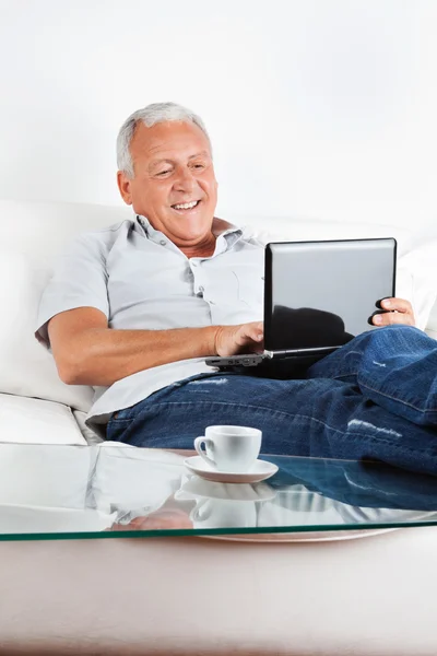 Hombre mayor relajado que trabaja en el ordenador portátil — Foto de Stock