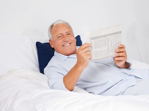 Расслабленный человек, читающий газету — стоковое фото