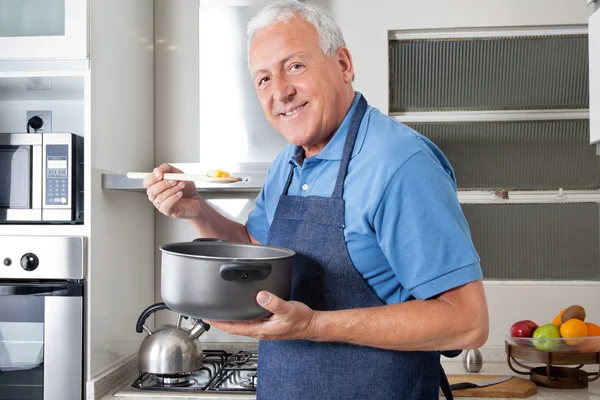 Senior man proeverij voedsel — Stockfoto