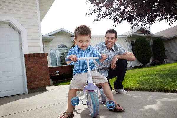 Pai ensinando Filho a montar um triciclo — Fotografia de Stock