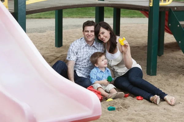 Paret sitter med sonen på lekplats — Stockfoto