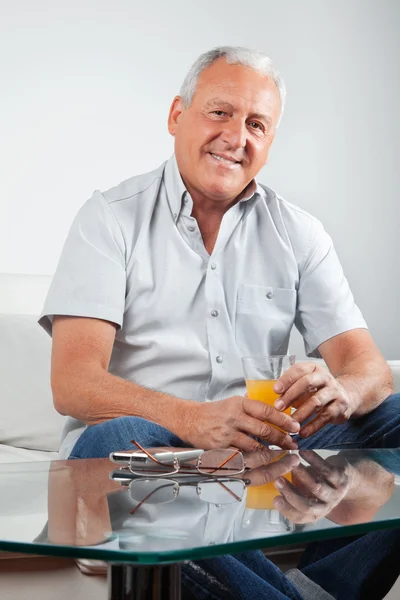 Старший человек держит стакан апельсинового сока — стоковое фото