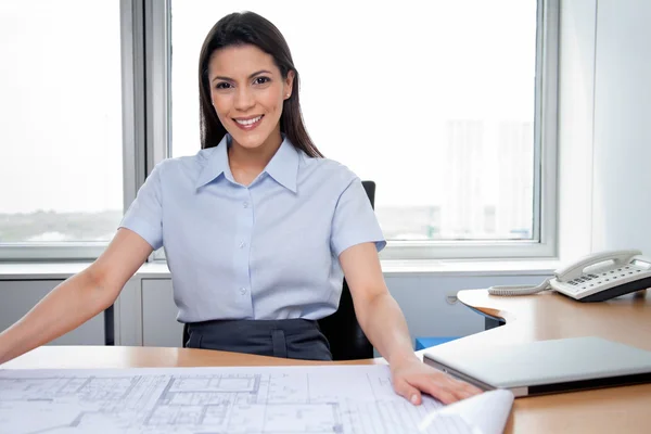 Vrouwelijke architect zitten met blauwdrukken op Bureau — Stockfoto