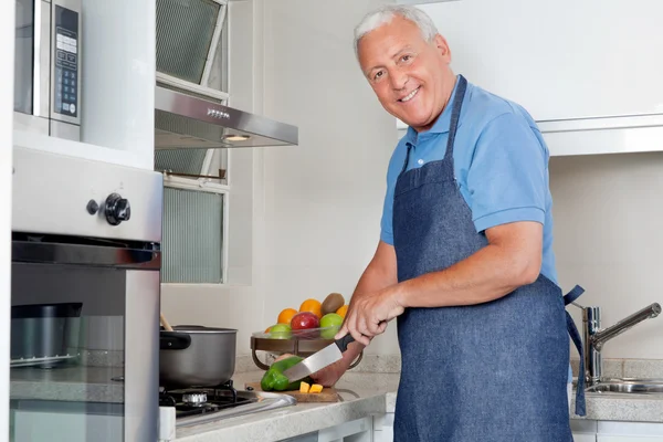 Hombre cortando verduras en el mostrador de cocina — Foto de Stock