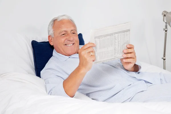 Расслабленный пожилой человек читает газету — стоковое фото
