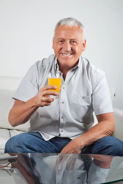Äldre man har färsk apelsinjuice — Stockfoto