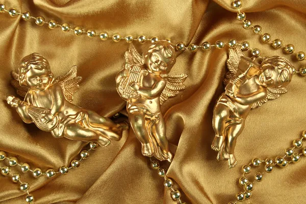 Three angels on a golden fabric — Stock Photo, Image