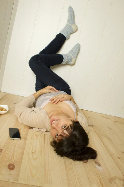 Ung kvinna liggande på golvet i huset — Stockfoto