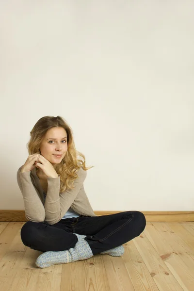 Młoda kobieta siedzi na podłodze w domu — Zdjęcie stockowe