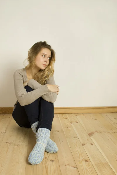 Молодая женщина, сидящая дома на полу — стоковое фото