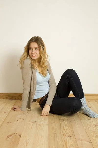 Młoda kobieta siedzi na podłodze w domu — Zdjęcie stockowe