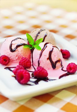 Ice cream in a plate decorated with mint and raspberries clipart