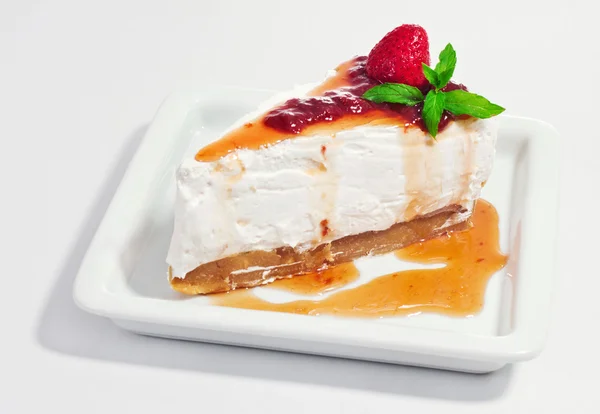 Cheesecake décoré avec de la menthe et de la confiture de fraises sur fond blanc — Photo