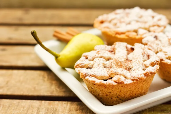 Closeup of mini pies on a plate decorated with cinnamon and a pear — Stock Photo, Image
