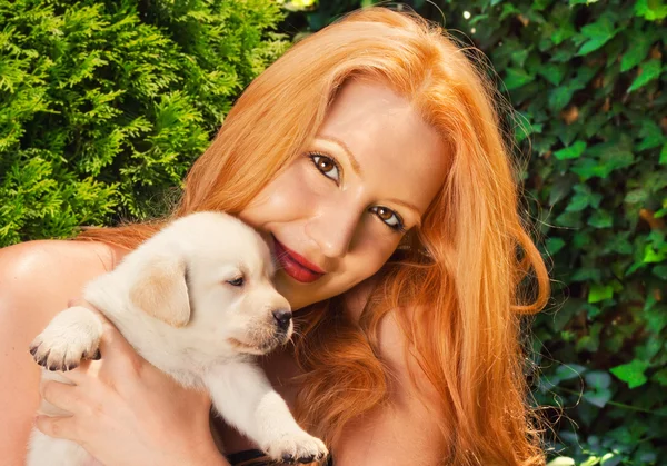 Rossa con in braccio un simpatico cucciolo labrador — Foto Stock