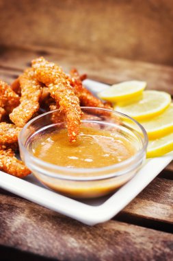 Chicken fingers served with honey-mustard dip and lemon slices clipart