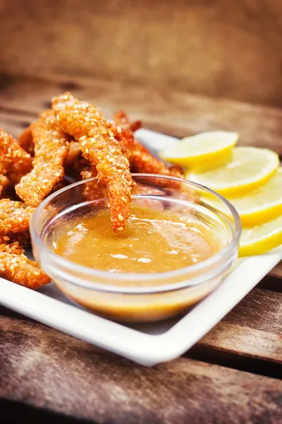 Dedos de pollo servidos con salsa de miel y mostaza y rodajas de limón —  Fotos de Stock