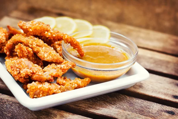 Kyckling fingrar serveras med honung-Senap dopp och citronskivor — Stockfoto