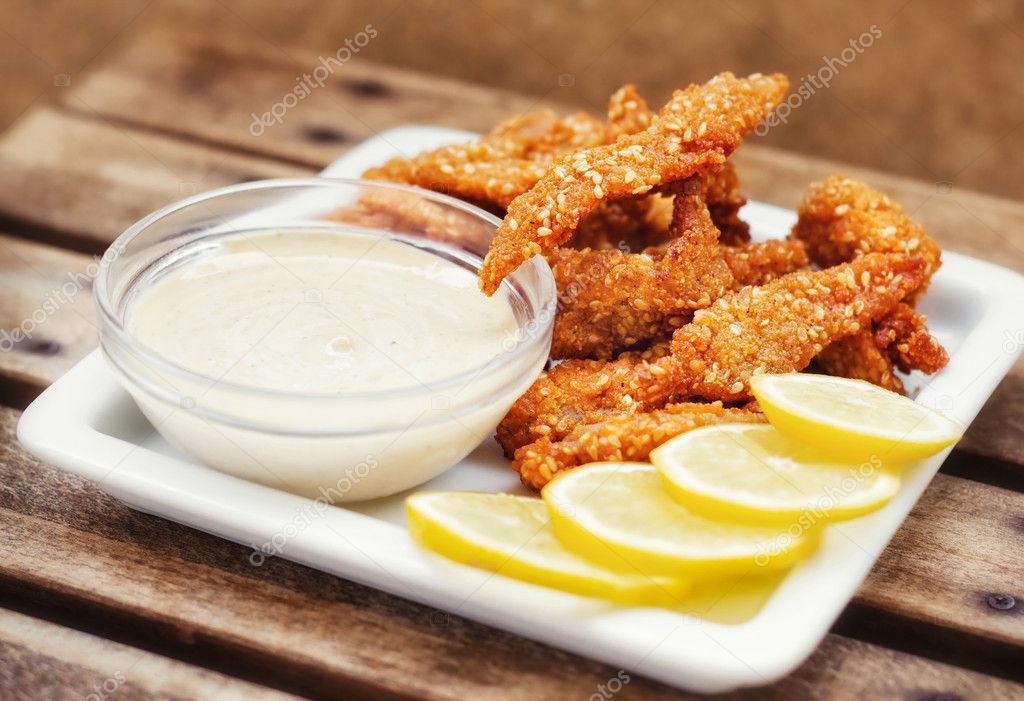 Chicken fingers served with tartar sauce and lemon slices