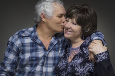 Older couple: elderly man kisses the old woman - love concept clipart