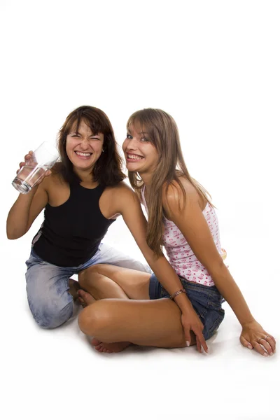Two cheerful girls hold a glass with water — Stock Photo, Image