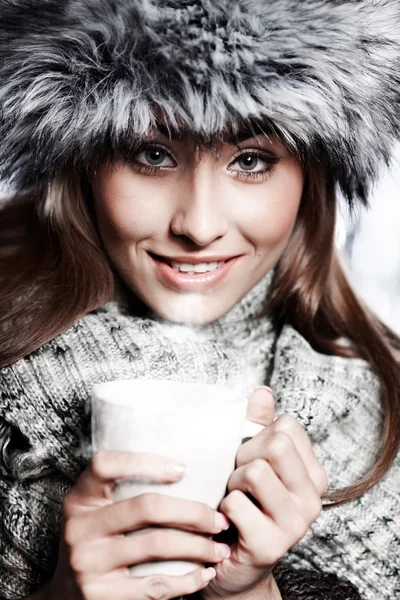 Menina soprando em bebida quente vestida com roupas de inverno — Fotografia de Stock