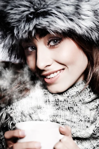 Chica soplando en la bebida caliente vestida con ropa de invierno — Foto de Stock