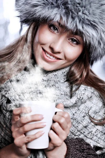 Chica soplando en la bebida caliente vestida con ropa de invierno —  Fotos de Stock